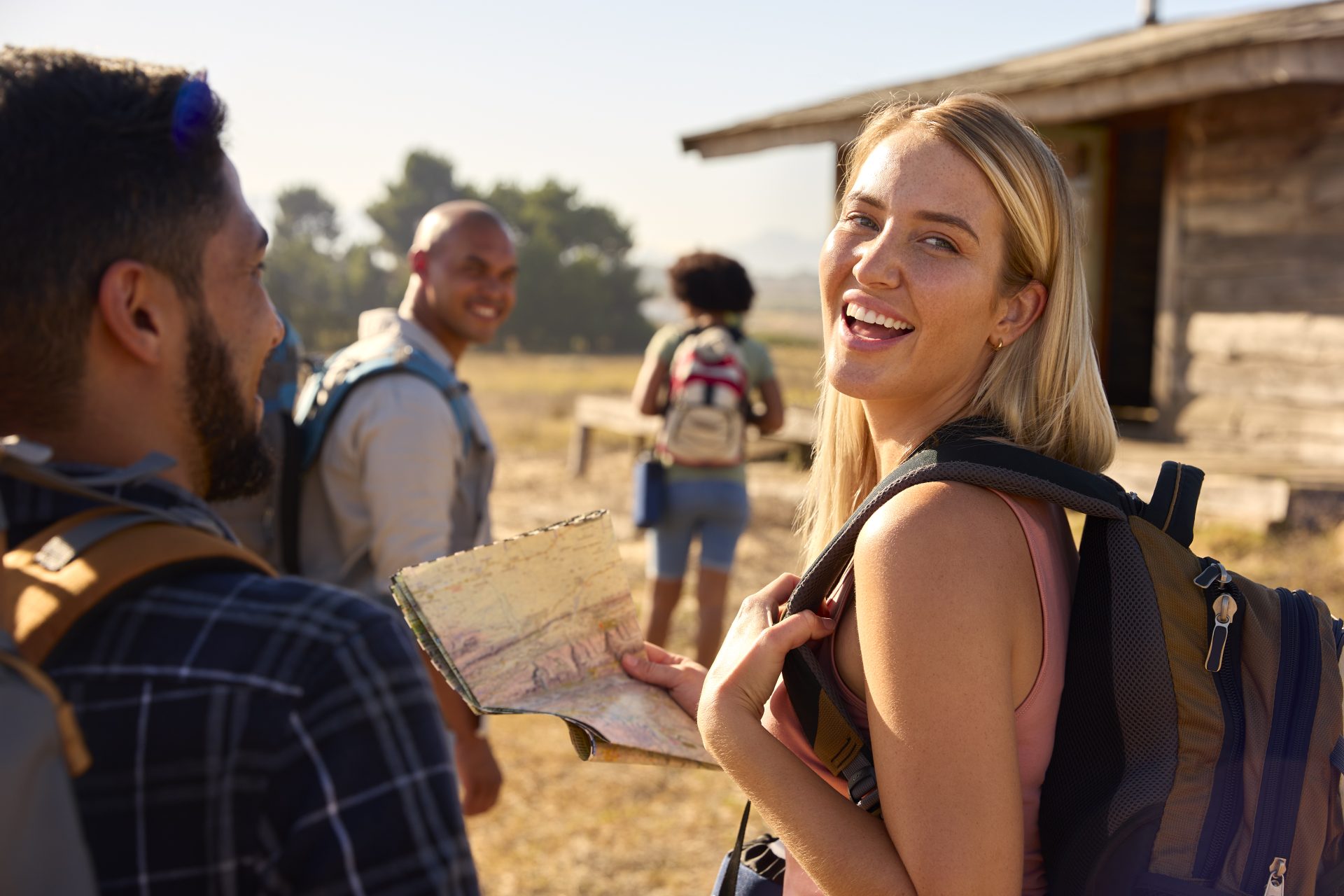 Portrait Of Group Of Friends With Map And Backpacks Hiking In Countryside Together